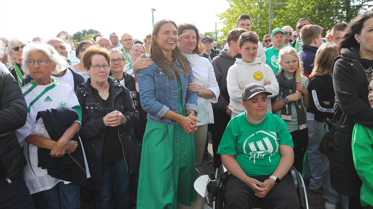 Tochter und Frau von Krzysztof Nowak stehen gemeinsam mit VfL Wolfsburg Fans zusammen.