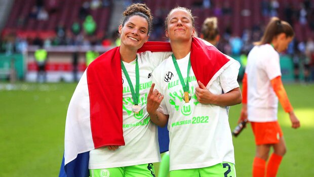 VfL-Wolfsburg-Spielerinnen Dominique Janssen und Lynn Wilms mit einer Niederlande-Flagge.