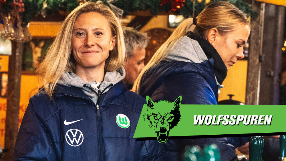 Die VfL-Wolfsburg-Spielerinnen Rebecka Blomqvist und Merle Frohms stehen in einer Hütte vom Weihnachtsmarkt Wolfsburg.