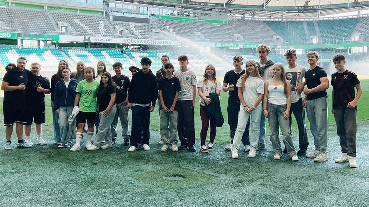 Schüler und Schülerinnen posieren im Rahmen der Begegnungsinitiative „Rudelbildung“ gemeinsam im Innenraum der Volkswagen Arena.