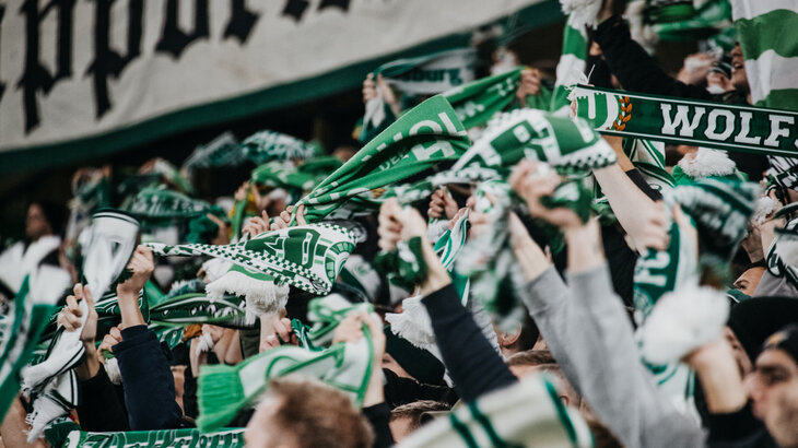 Die Fans des VfL Wolfsburg wedeln mit ihren Fanschals.