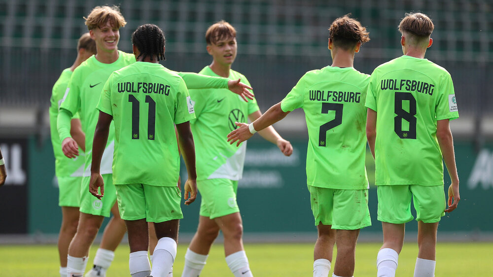 Die U17-Spieler des VfL Wolfsburg gehen nebeneinander und klatschen sich ab.