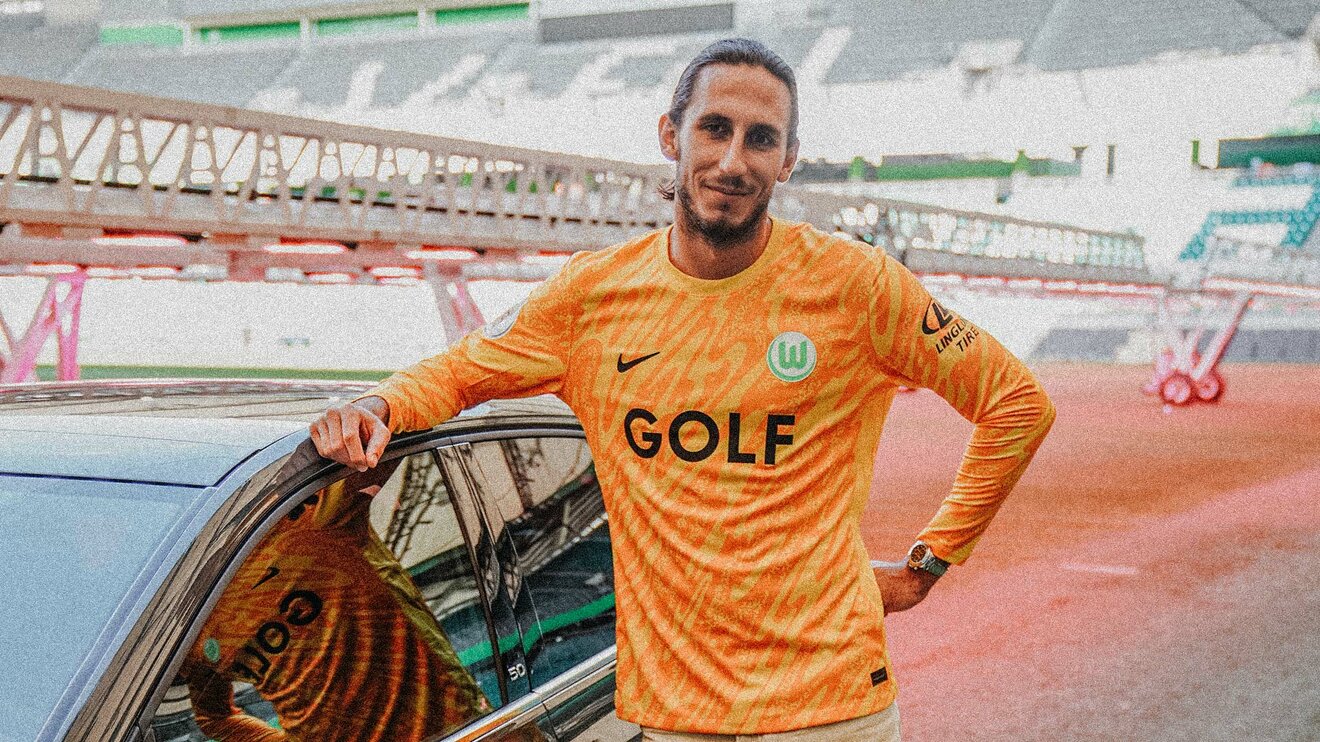 VfL-Wolfsburg-Torhüter Kamil Grabara posiert in der Volkswagen Arena neben einem Auto für ein Bild.