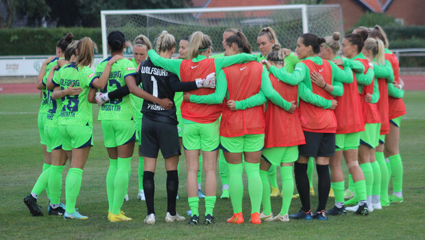 Die VfL Wolfsburg-Spielerinnen stehen vor dem Spiel im Kreis zusammen.
