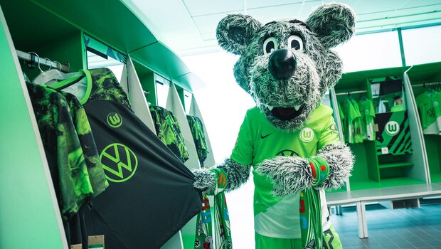 Das Maskottchen des VfL Wolfsburg präsentiert das neue Trikot in der Umkleidekabine.