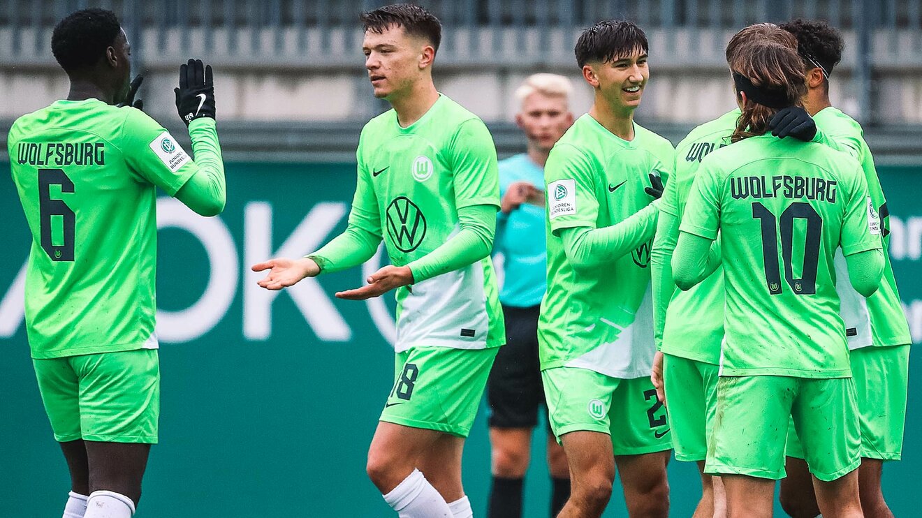 Die Spieler der U19-Mannschaft des VfL Wolfsburg stehen jubelnd beisammen und klatschen sich ab.