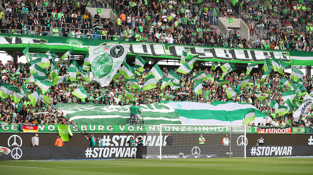 In der Fankurve des VfL Wolfsburg in der Volkswagen Arena werden zahlreichen Fahnen geschwungen. 