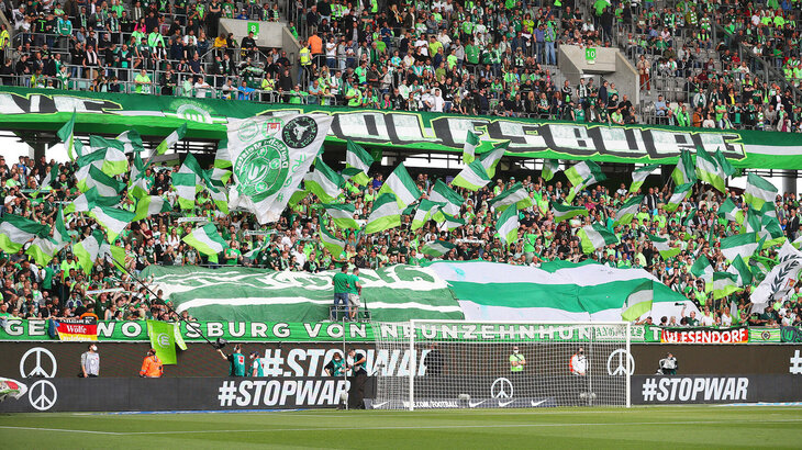 In der Fankurve des VfL Wolfsburg in der Volkswagen Arena werden zahlreichen Fahnen geschwungen. 