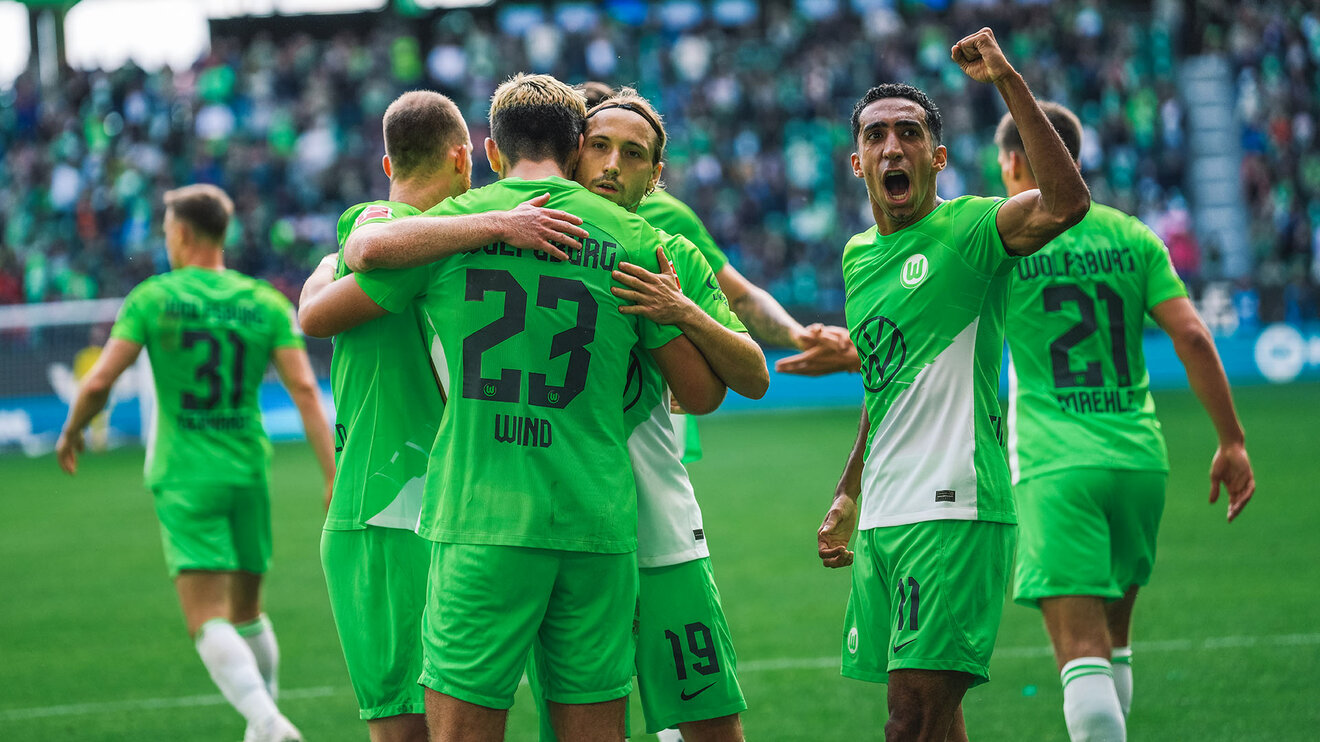 Die Spieler des VfL Wolfsburg stehen jubelnd beisammen.