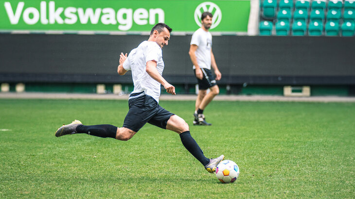 Ein Mann in der Volkswagen Arena des VfL Wolfsburg holt zum Schuss aus.
