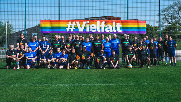 Die Mannschaft des VfL-Wolfsburg steht gemeinsam unter einem Banner mit der Aufschrift Vielfalt.