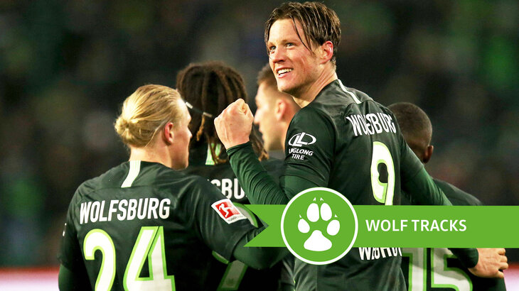 Die Spielerinnen des VfL Wolfsburg bejubeln gemeinsam ihren Treffer. Daneben der Schriftzug Wolfsspuren.