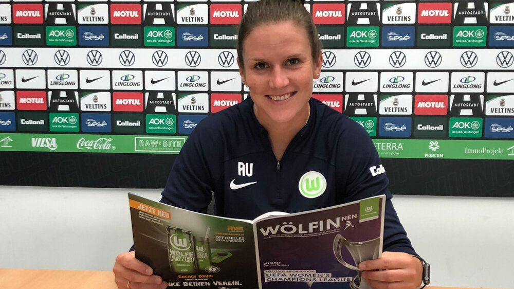 Alisa Vetterlein hält ein Magazin des VfL Wolfsburg in den Händen.
