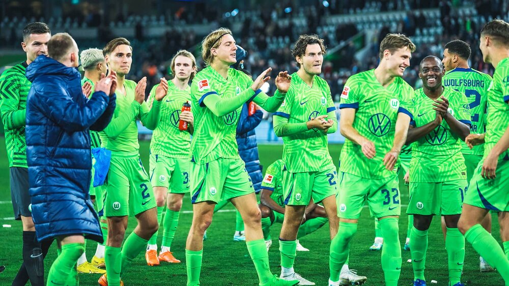 Die Mannschaft des VfL-Wolfsburg stehen Gemeinsam auf dem Spielfeld und freuen sich über ein gewonnenes Spiel.