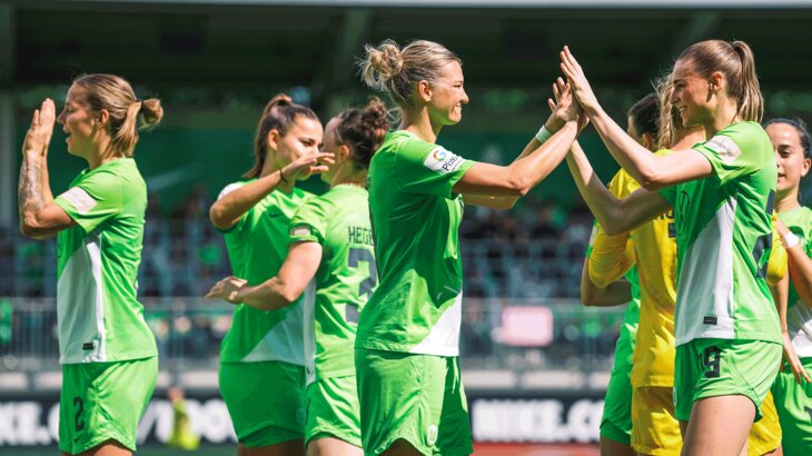 Die Spielerinnen des VfL Wolfsburg stehen jubelnd beisammen. 