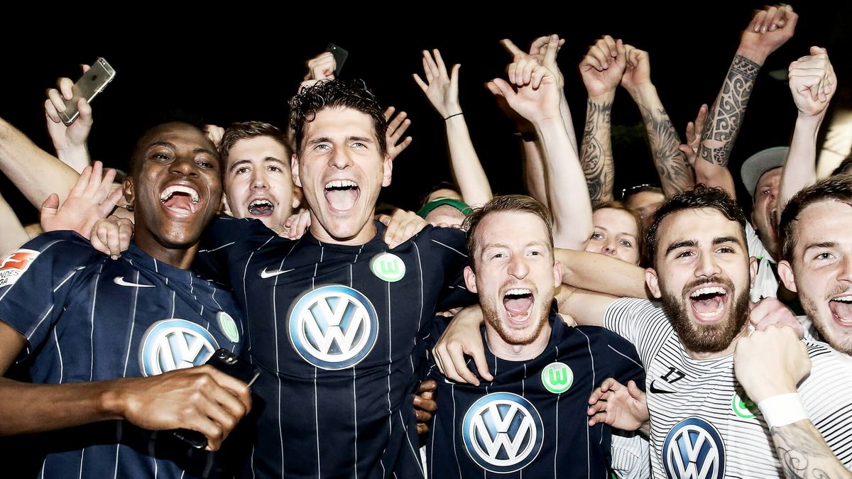 VfL Wolfsburg-Spieler und Fans liegen sich in den Armen und bejubeln den Sieg im Relegationsrückspiel 2017.