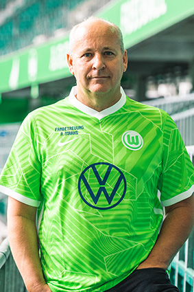 Ein Fanbeauftragter des Vereins im VfL Wolfsburg-Trikot.