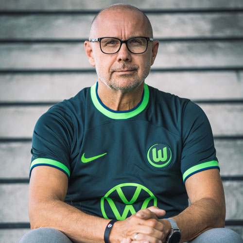 Der Fanbeauftragte Carsten im VfL Wolfsburg-Trikot auf einer Treppe. Der Fanbeauftragte Carsten sitzt im VfL Wolfsburg-Trikot auf einer Treppe.