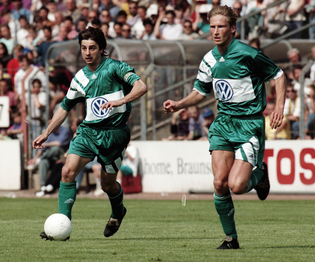 Siggi Reich und Detlev Dammeier laufen nebeneinander in einem Spiel des VfL Wolfsburg. 
