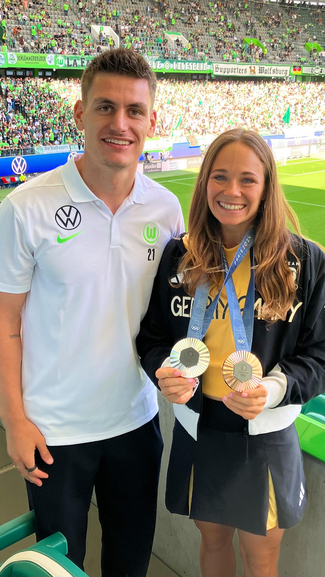 Olympiasiegerin Paulina Paszek posiert mit Joakim Maele in der Volkswagen Arena und hält ihre Medaillen in die Kamera.